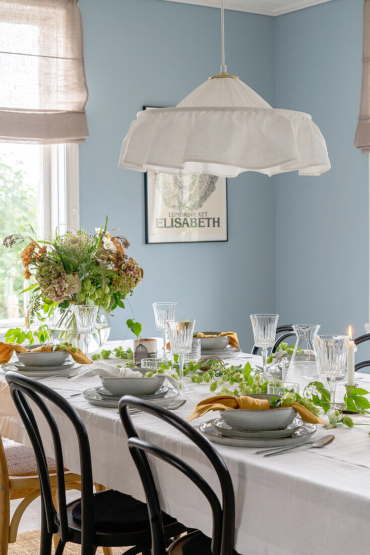 Set dining table with tablecloth and vintage lamp in dining room with light blue painted walls