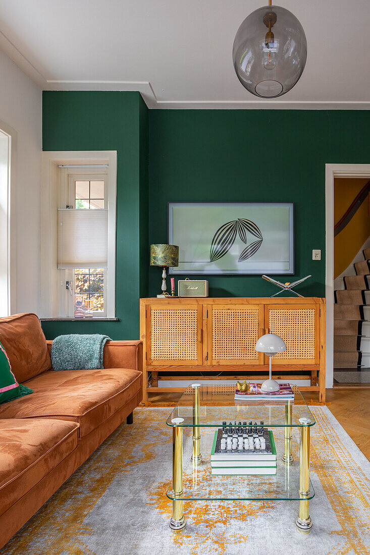 Living room with green wall, rattan cabinet and leather sofa