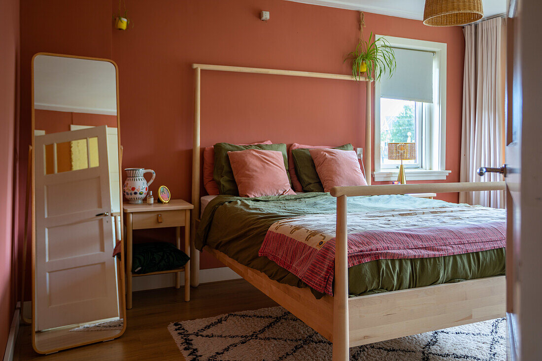 Bedroom with terracotta wall, wooden bed and patterned carpet