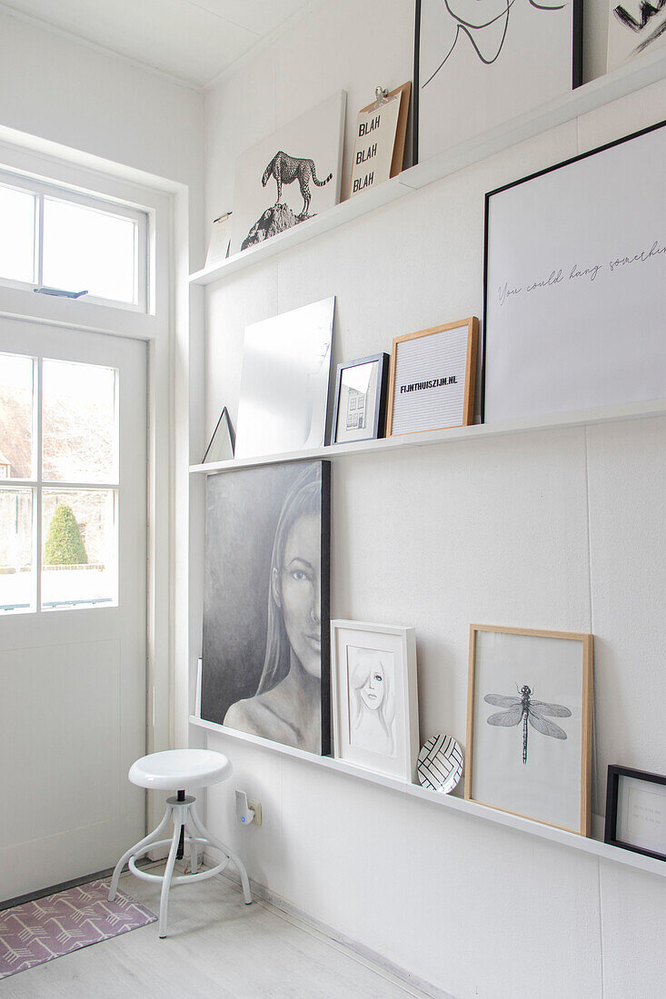 White shelf with various pictures in a light-coloured hallway