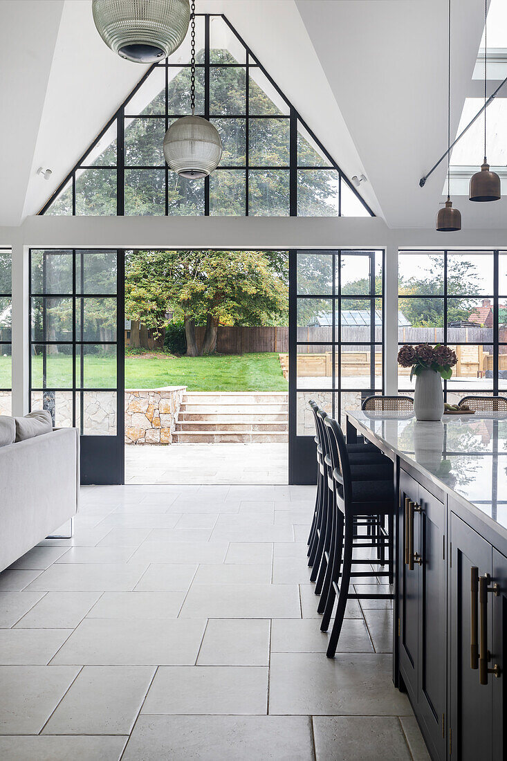 Moderne Küche mit Glas-Pendelleuchten und Glastüren zum Garten