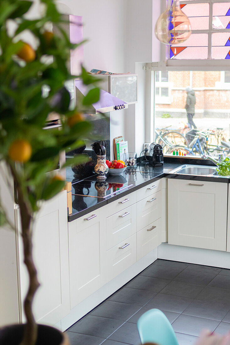 Light-coloured kitchen with white cupboards and black worktop