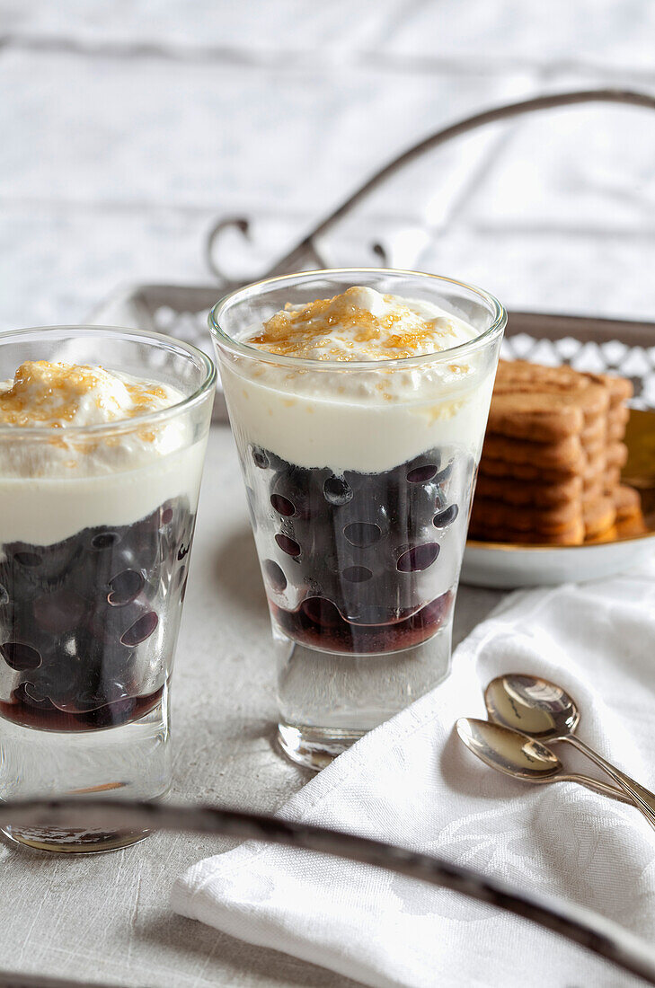 Schichtbecher mit Kirschen und gezuckerter Sahne