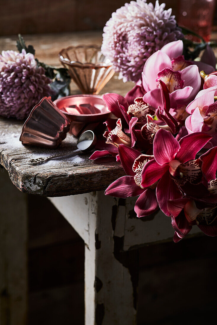 Verschiedene Blüten und Puddingförmchen auf Holztisch