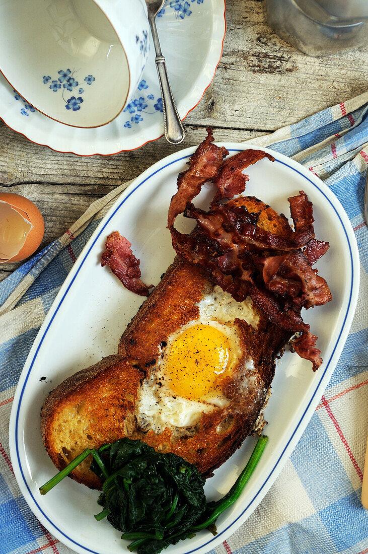 Brunch with fried egg in toast, bacon and spinach