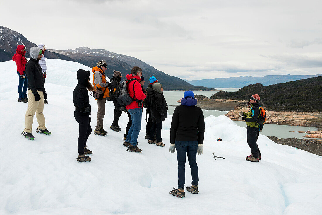 Touristen hören einem Führer zu, während sie auf einem Gletscher im Nationalpark Los Glaciares stehen; Provinz Santa Cruz, Argentinien