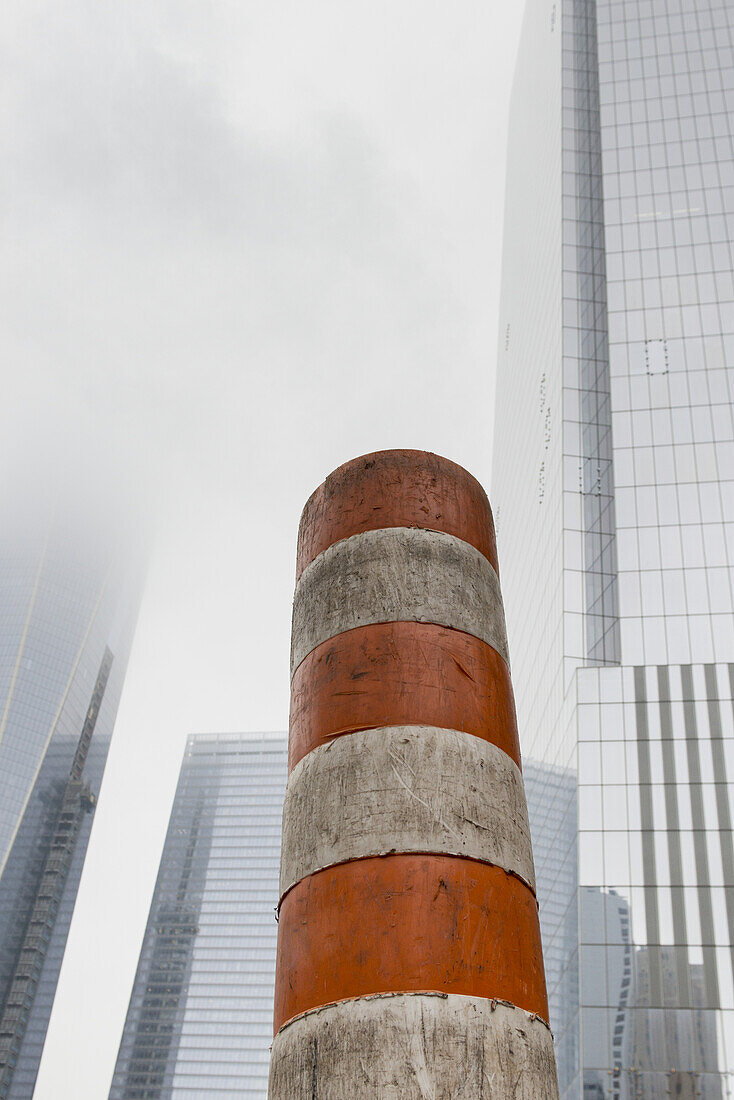 Schmutzige orange-weiß gestreifte Baustelle mit Wolkenkratzern im Hintergrund; New York City, New York, Vereinigte Staaten von Amerika