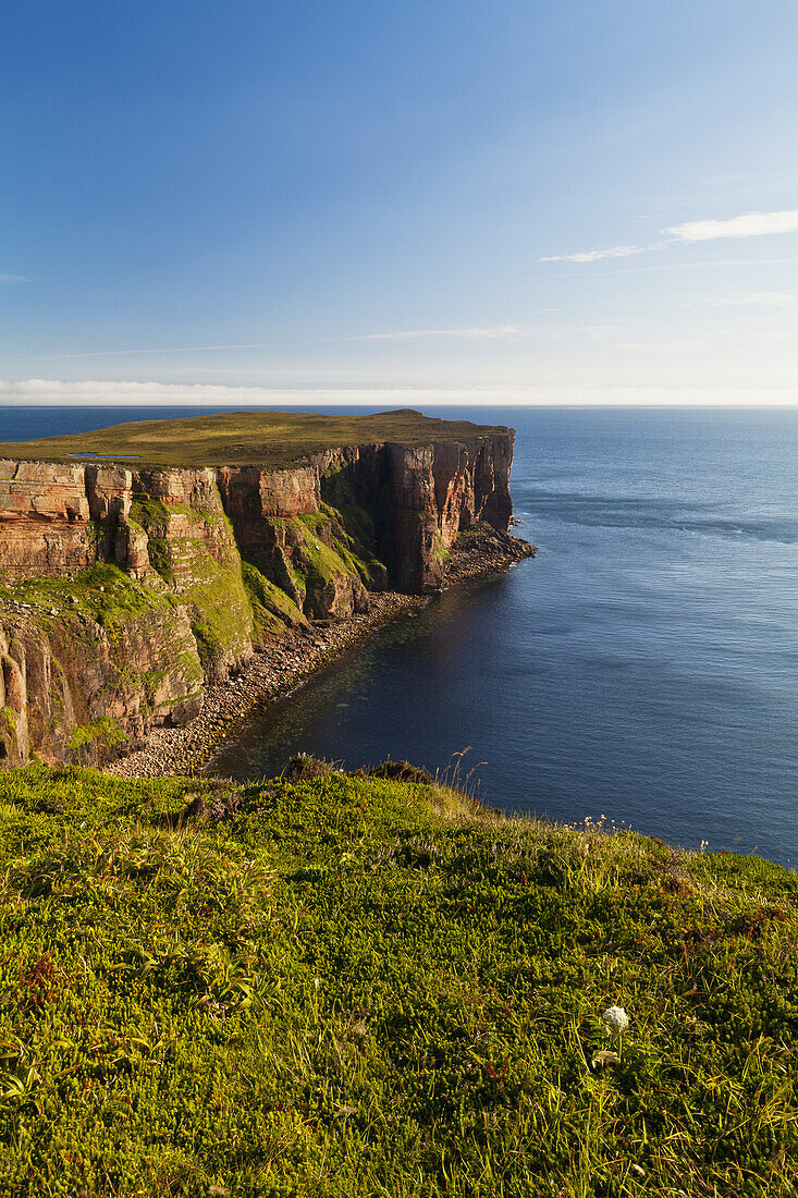 Klippe entlang der Küstenlinie und Blick auf das Meer und den blauen Himmel; Orkney, Schottland