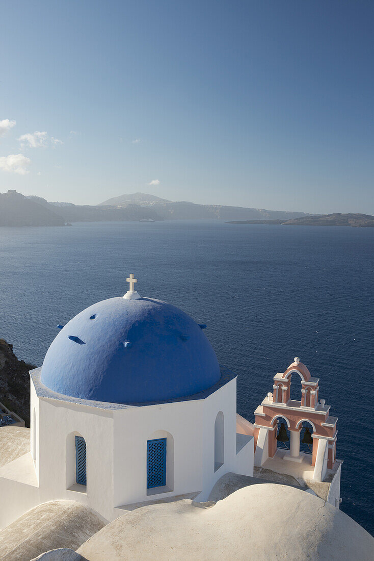 Eine blaue Kuppelkirche und ein rosafarbener Glockenturm mit Blick auf die Caldera; Oia, Santorin, Kykladen, Griechische Inseln, Griechenland