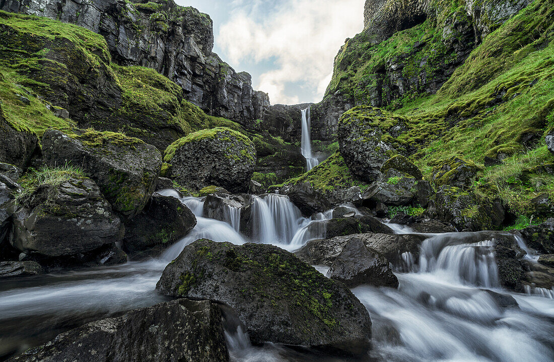 Ein unbenannter Bach fließt über eine Felswand und erzeugt einen wunderschönen Wasserfall nach einer Periode starker Regenfälle; Island