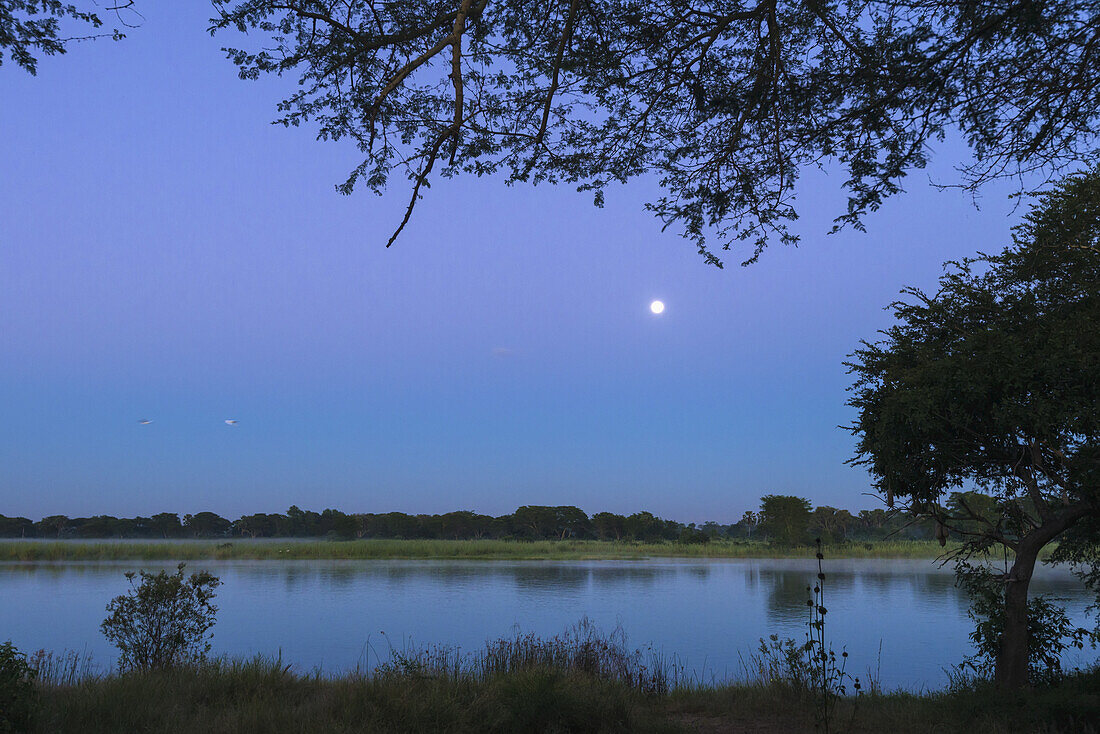 Monduntergang über dem Shire River bei Sonnenaufgang, Liwonde National Park; Malawi