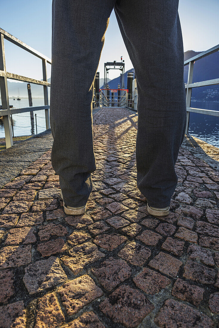 Man Standing On A Stone Walkway On The Waterfront; Locarno, Ticino, Switzerland