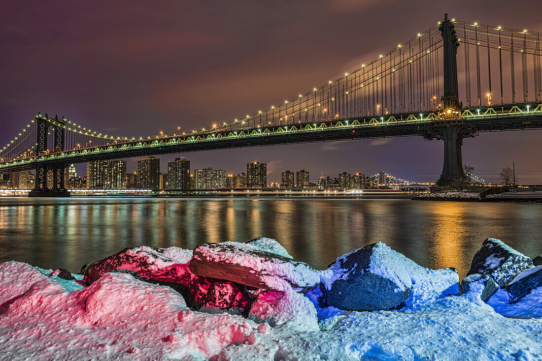 Manhattan Bridge By Snow-Covered Rocks At Sunset, Brooklyn Bridge Park; Brooklyn, New York, Vereinigte Staaten Von Amerika
