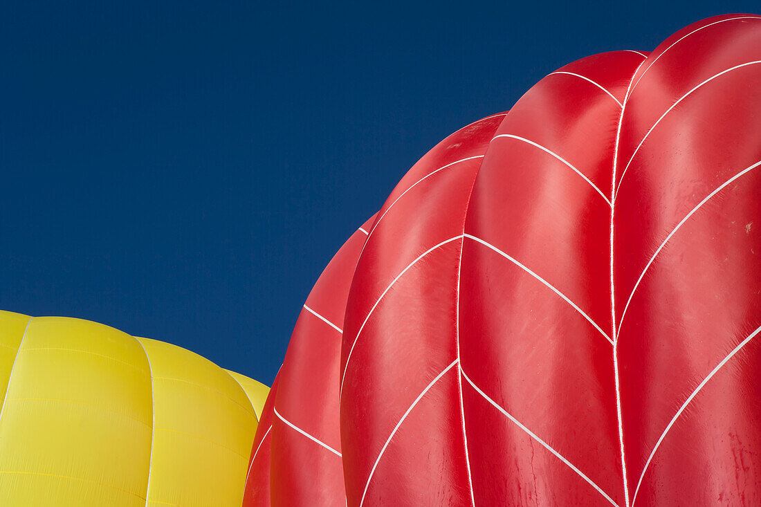 Gelbe und rote Heißluftballons steigen in den Himmel, während sie sich mit heißer Luft füllen und zum Abheben bereit machen; Filzmoos, Österreich