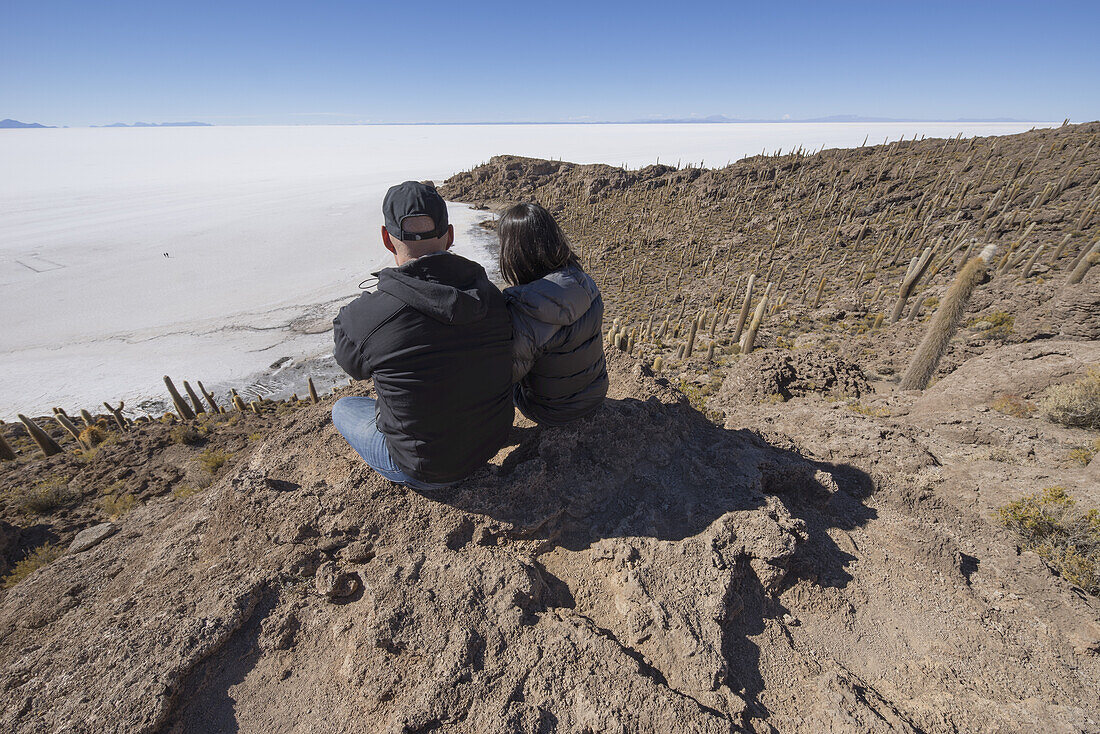 Paar sitzt auf einer Insel aus Felsen und Kakteen namens Incahuasi; Uyuni, Bolivien