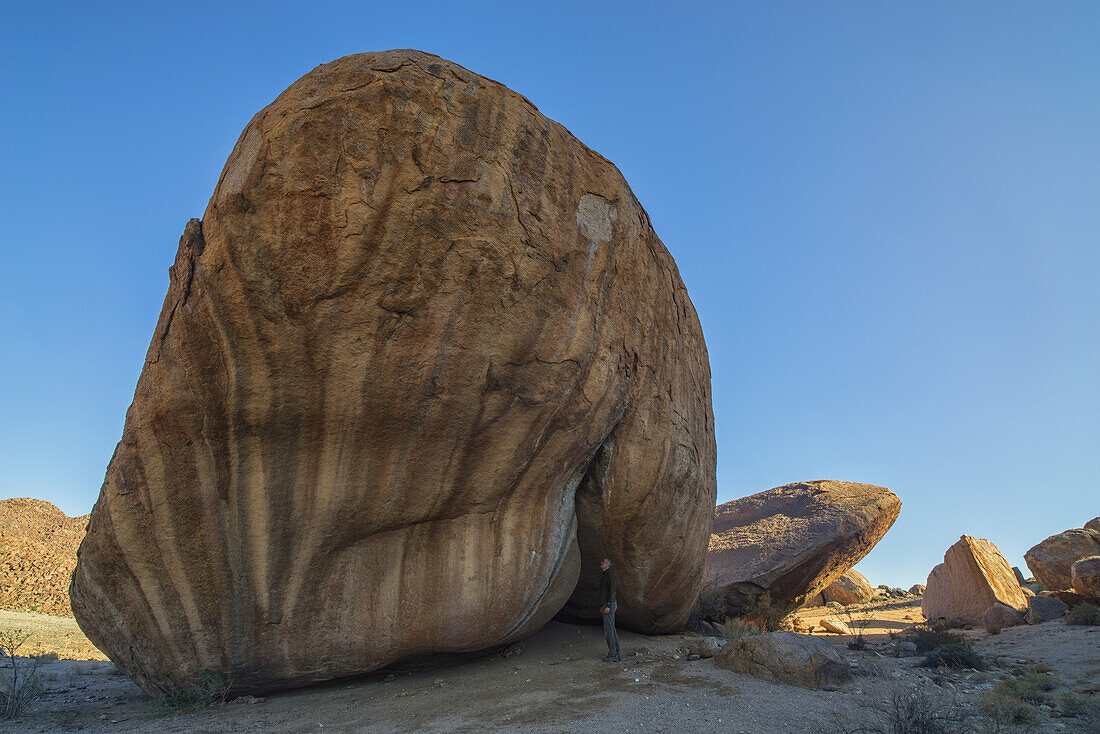 Person, die unter einem großen Felsbrocken im Richtersveld-Nationalpark steht; Südafrika