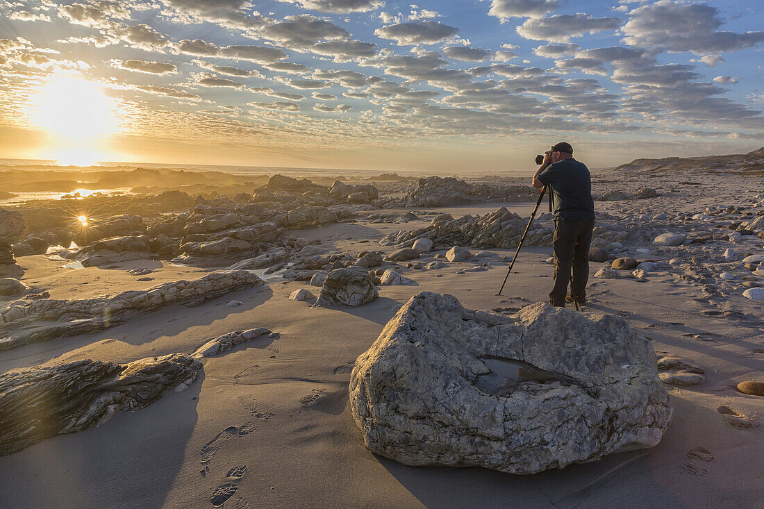 Mann, der am Marmorstrand im Namakwaland-Nationalpark steht und Fotos macht; Südafrika
