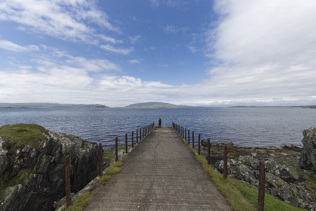 Person, die am Ende eines Pfades am Wasser steht und auf das Wasser hinausschaut; Argyll und Bute, Schottland