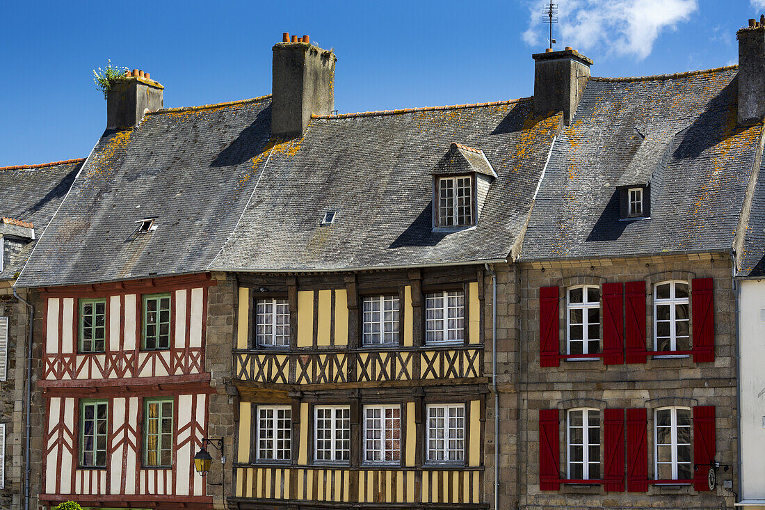Nahaufnahme von bunt bemalten Fachwerkgebäuden und Fensterläden mit blauem Himmel und Wolken; Treguier, Bretagne, Frankreich