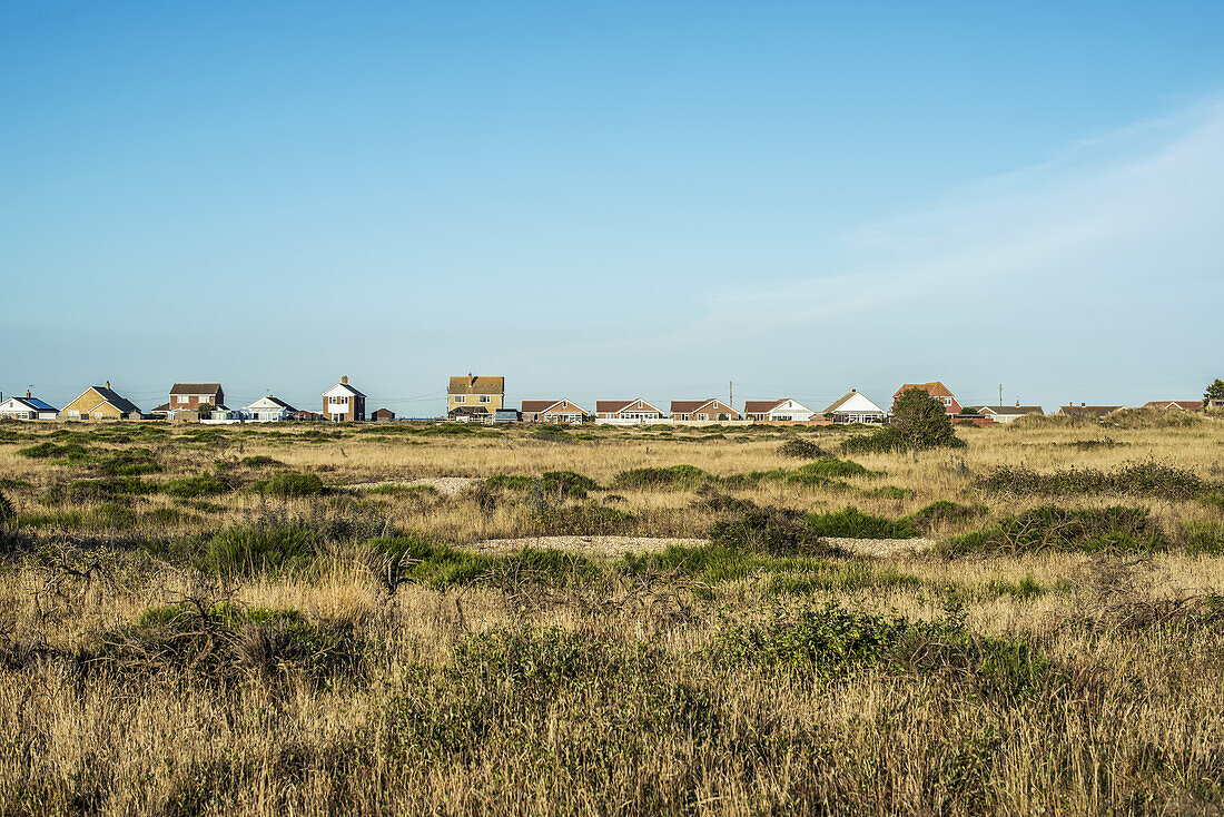 Houses In The Distance Viewed Over A Grass Field; Dungeness, Kent, England