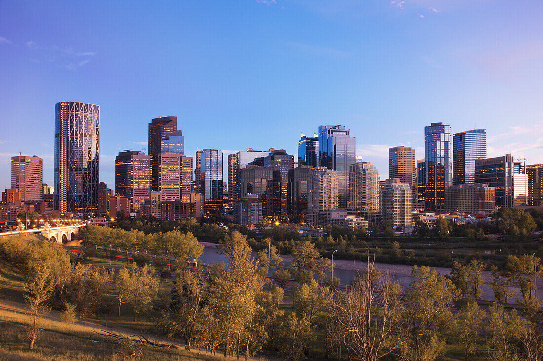 Modern City Skyline At Sunset With Lit Skyscrapers; Calgary, Alberta, Canada