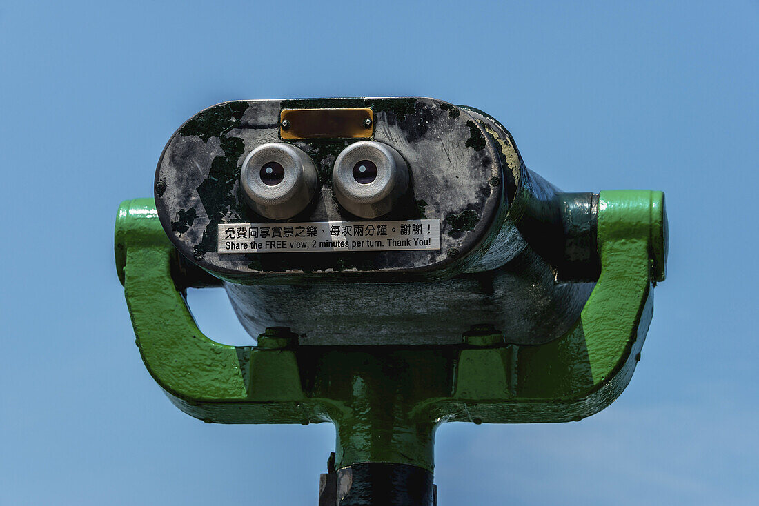 Green, Metal Public Binoculars Pointing Towards Blue Sky With Instructions Written In English And Chinese; Hong Kong