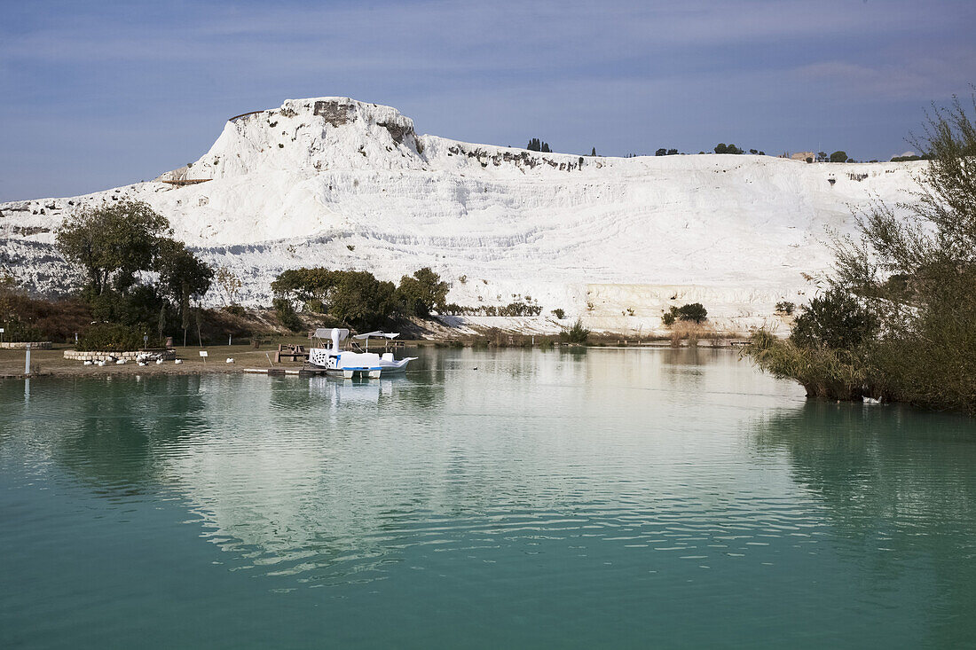Turquoise Water In A Pool Reflecting A White Wall Of Mineral Deposits; Pamukkale, Turkey