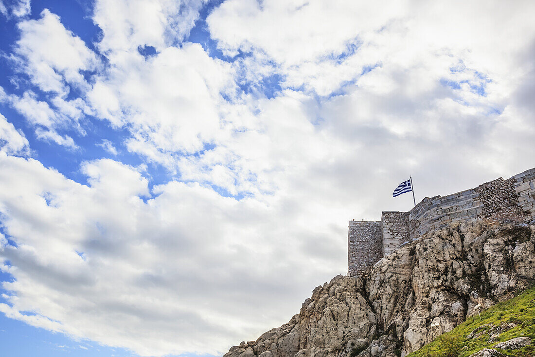 Felsklippe, Steinmauern und eine griechische Flagge; Athen, Griechenland