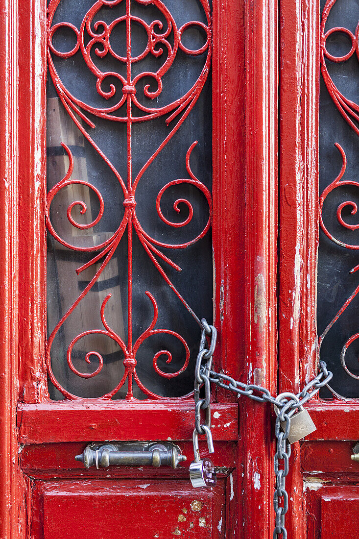 Rote Tür mit dekorativen Fenstern, die mit einem Vorhängeschloss verschlossen ist; Athen, Griechenland