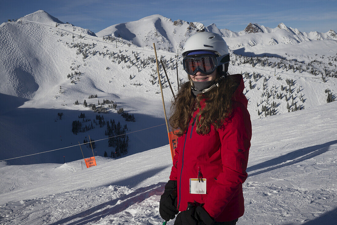 Girl Standing At A Ski Resort With The Canadian Rocky Mountains In The Background, Banff National Park; Alberta, Canada