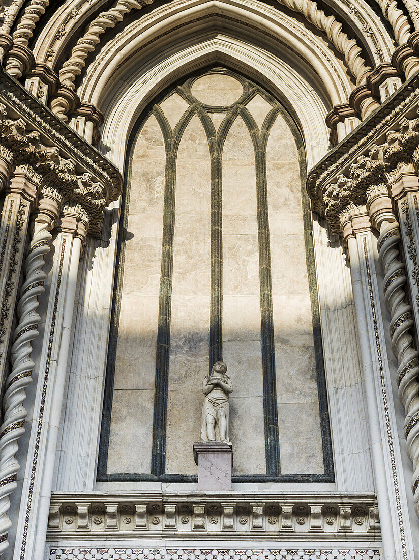 Statue eines Mannes auf einer verzierten Mauer mit gedrehten Säulen; Orvieto, Umbrien, Italien