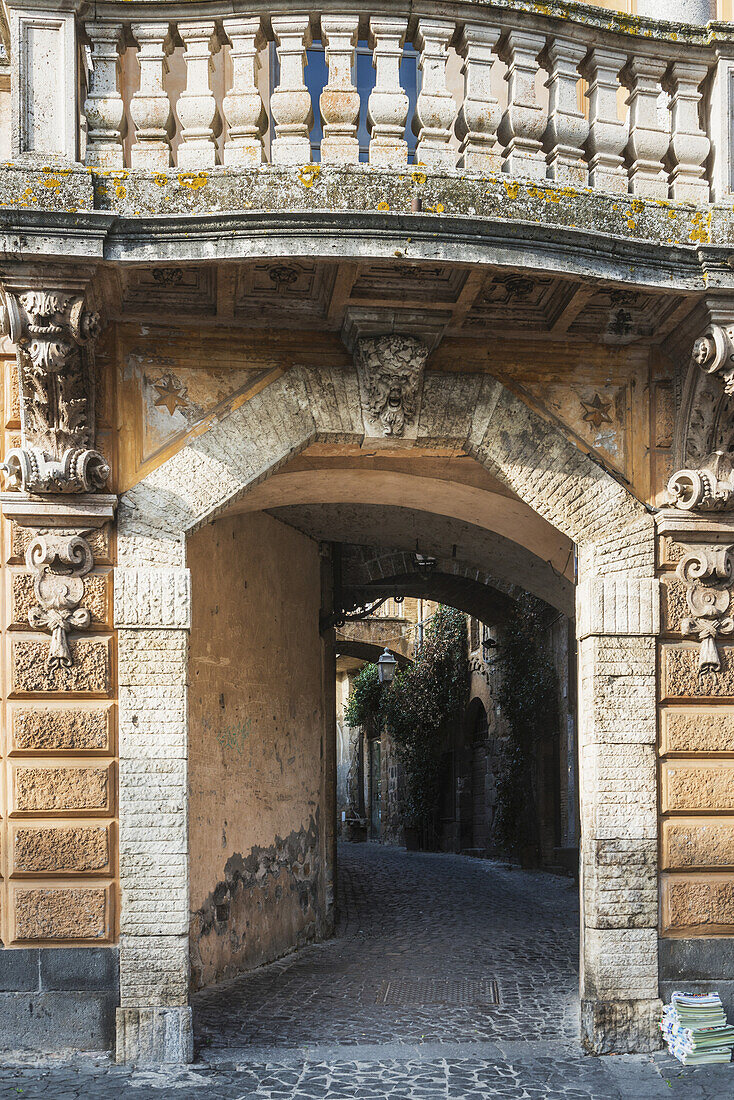 Fassade eines Gebäudes, die zu einem Gehweg mit Geländerstäben führt; Orvieto, Umbrien, Italien