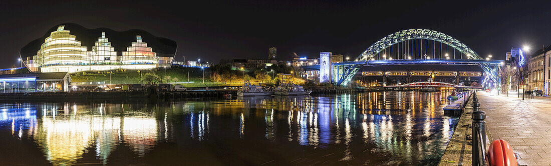 Nachts beleuchtete Tyne-Brücke über den Fluss Tyne und beleuchtete Gebäude; Newcastle, Tyne And Wear, England