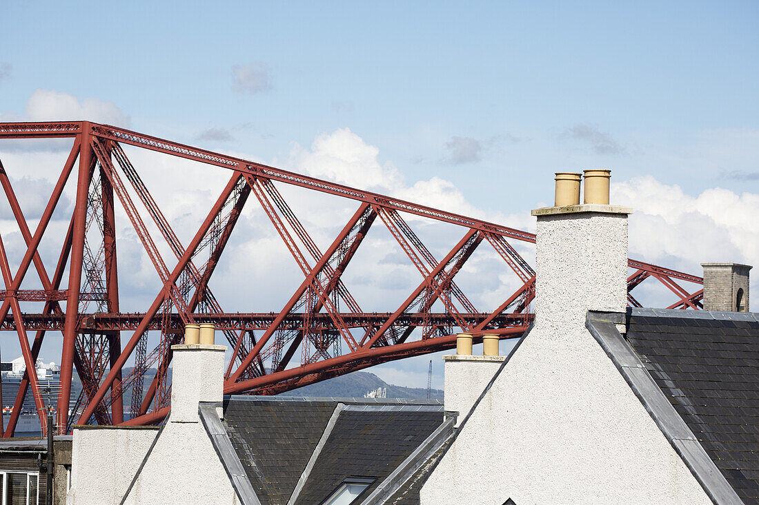 Red Metal Bridge With Houses And Chimneys In The Foreground; Edinburgh, Scotland