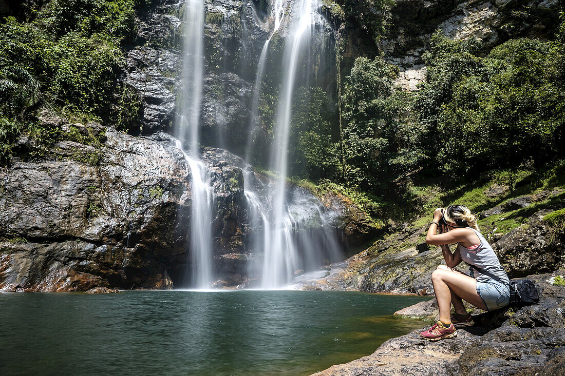 Eine junge Frau fotografiert den Wasserfall Cunca Rami; Flores, Indonesien