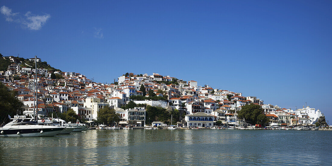 Häuser in einem Dorf und Boote in einem Hafen auf einer griechischen Insel; Panormos, Thessalia Sterea Ellada, Griechenland