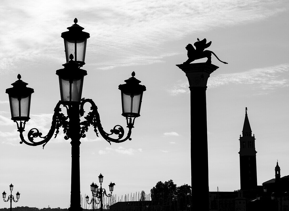 Silhouette Of An Ornate Lamp Post And Statue On A Column; Venice, Italy