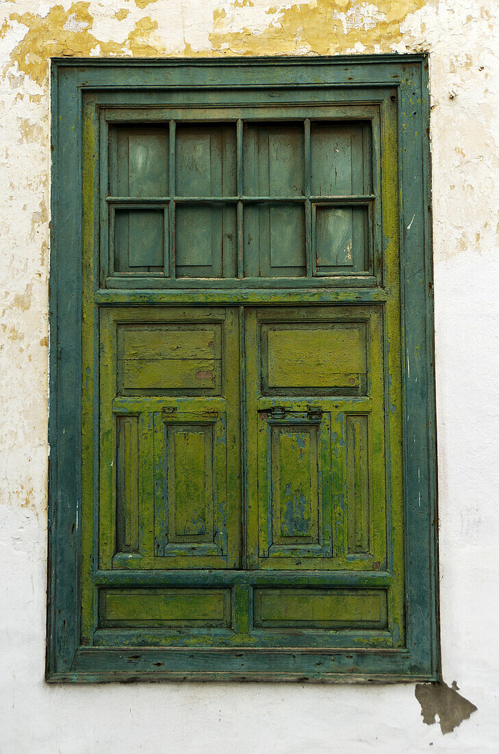 Verwittertes grünes Holzfenster mit hellgrünen Fensterläden in verwitterter weißer Stuckwand; Lanzarote, Kanarische Inseln, Spanien