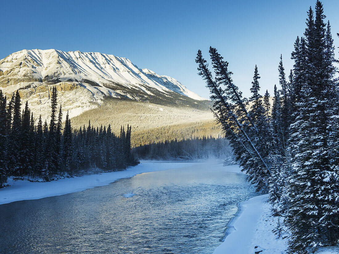 A Landscape With Snow Along The Shoreline Of A Lake And A Snow Covered Mountain; British Columbia, Canada