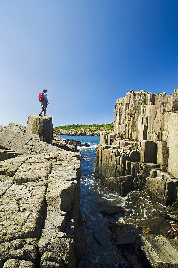 Hiker Along Basalt Rock Cliffs, Brier Island, Bay Of Fundy; Nova Scotia, Canada