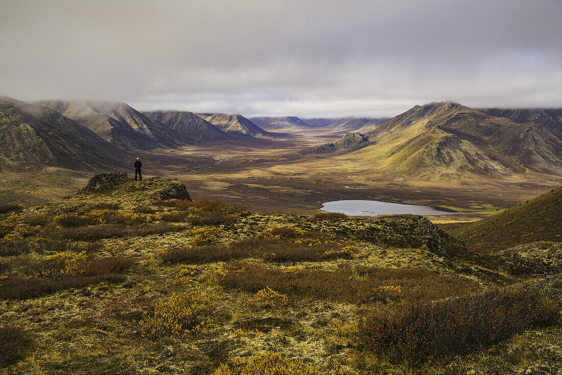 Mann steht auf einem Aussichtspunkt mit Blick auf das Blackstone Valley entlang des Dempster Highway; Yukon, Kanada