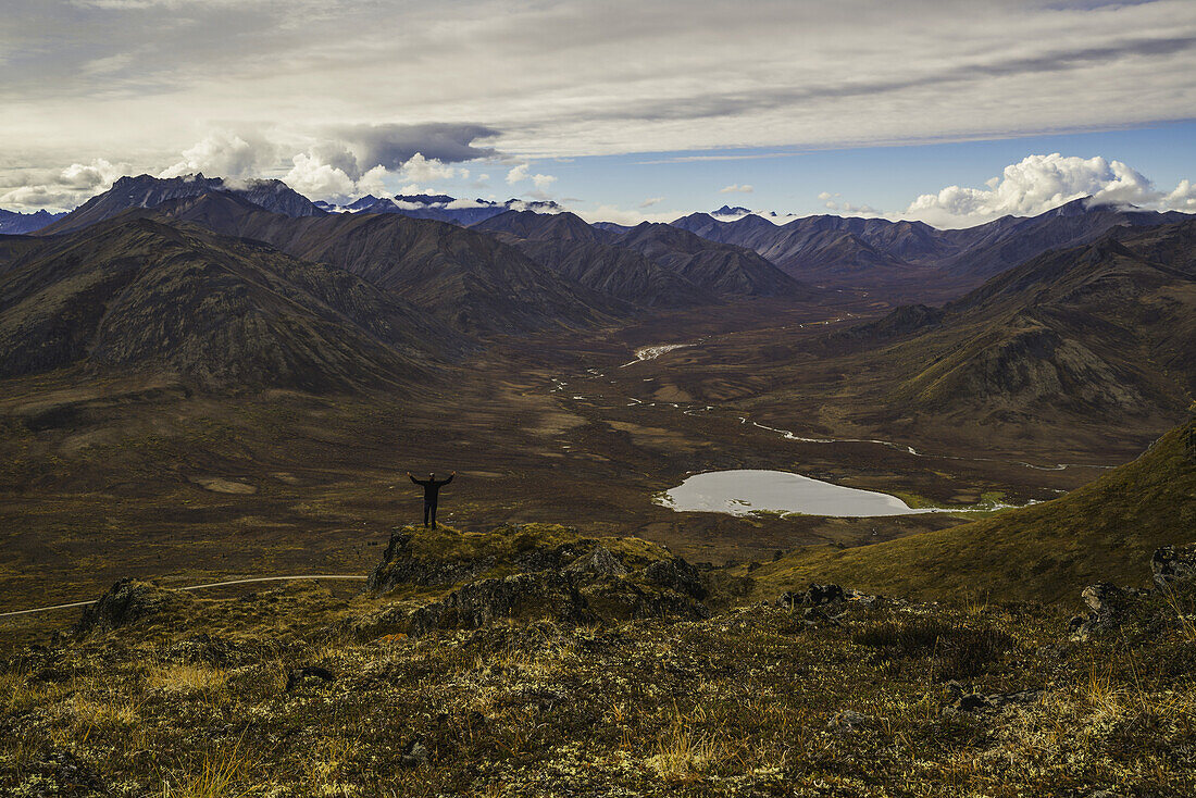 Mann steht auf einem Aussichtspunkt mit Blick auf das Blackstone Valley entlang des Dempster Highway; Yukon, Kanada