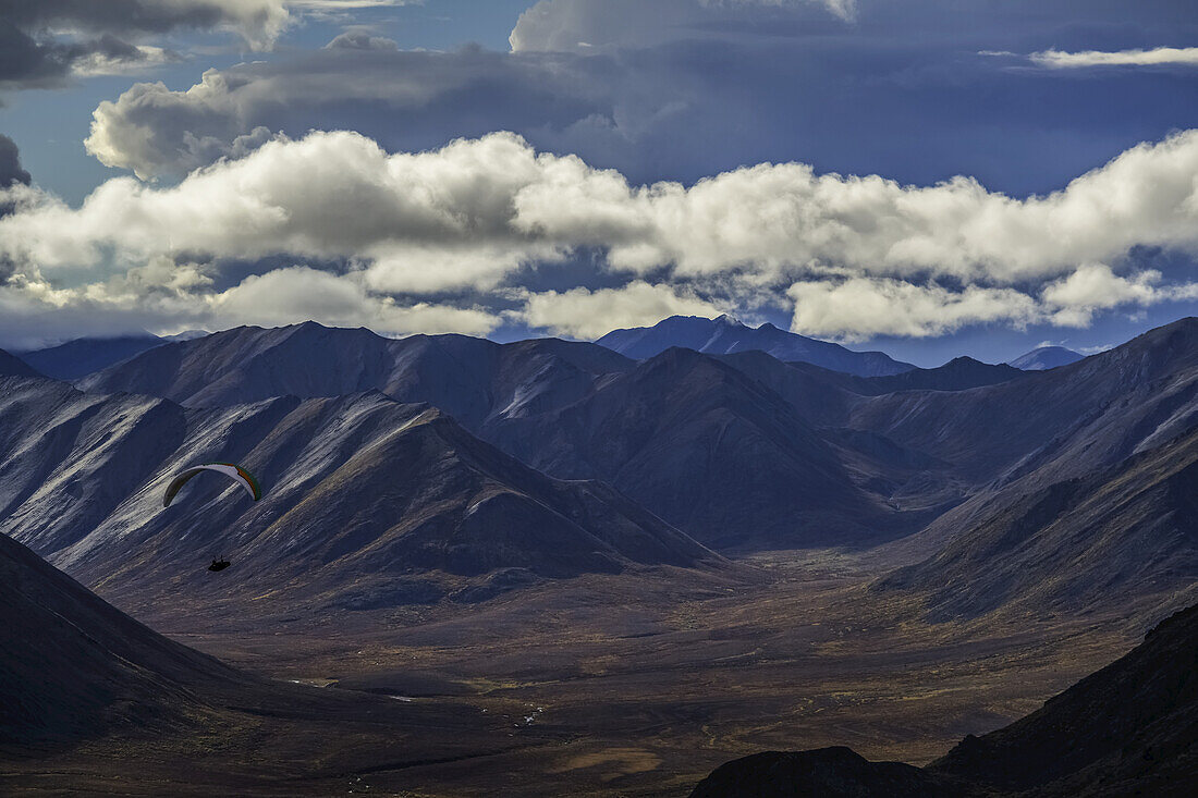 Man Paragliding Over The Mountain Of The Tombstone Range Along The Dempster Highway; Yukon, Canada