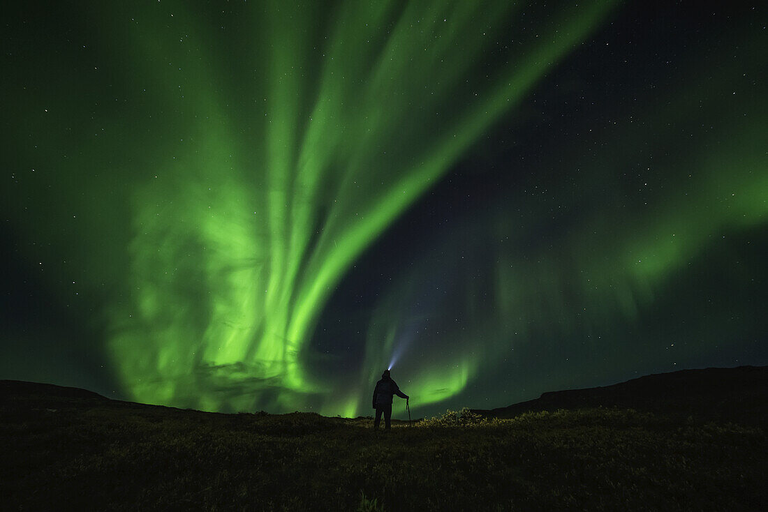 Mann, der unter den Nordlichtern steht, in der Nähe von Keno; Yukon, Kanada