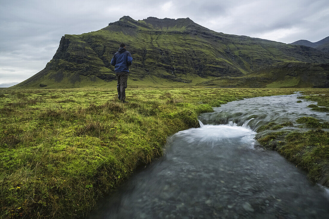 Man Standing In The Icelandic Wilderness Beside A Stream Along The South Coast Of Iceland; Iceland