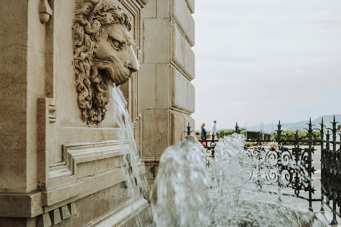 Wasserfontäne aus dem Maul eines Löwen an der Fassade eines historischen Gebäudes; Italien