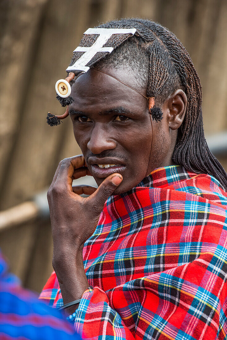 Porträt eines Massai-Kriegers mit geflochtener Frisur und traditioneller Kleidung in der Ngorongoro Conservation Area; Tansania