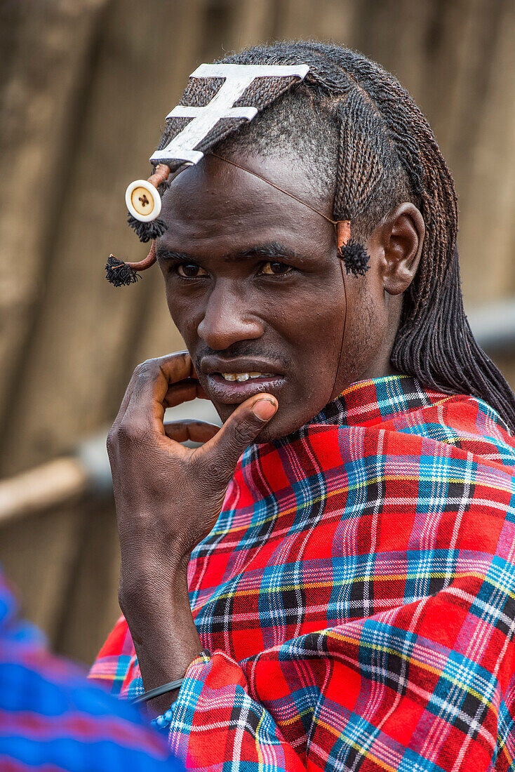 Portrait of Maasai warrior with braided hairstyle and wearing traditional clothing in the Ngorongoro Conservation Area; Tanzania