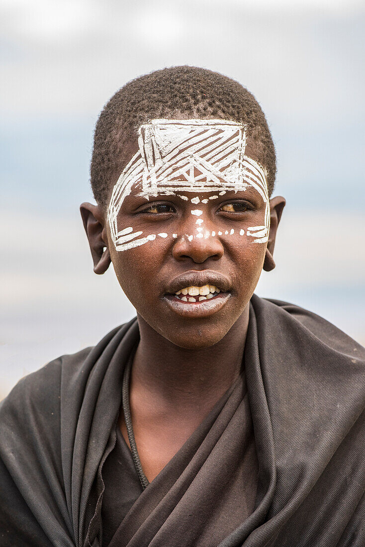 Maasai-Jugendlicher mit traditioneller Gesichtsbemalung, die anzeigt, dass er den Initiationsprozess für den Eintritt ins Erwachsenenalter abgeschlossen hat, im Ngorongoro-Schutzgebiet; Tansania