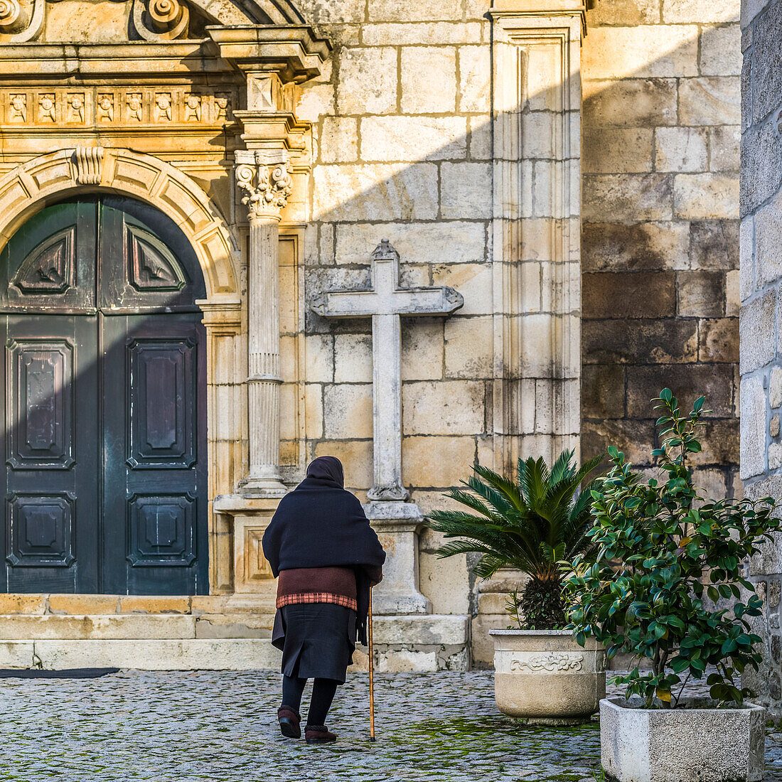 Ältere Frau nähert sich einer Kirche; Gemeinde Lamego, Bezirk Viseu, Portugal